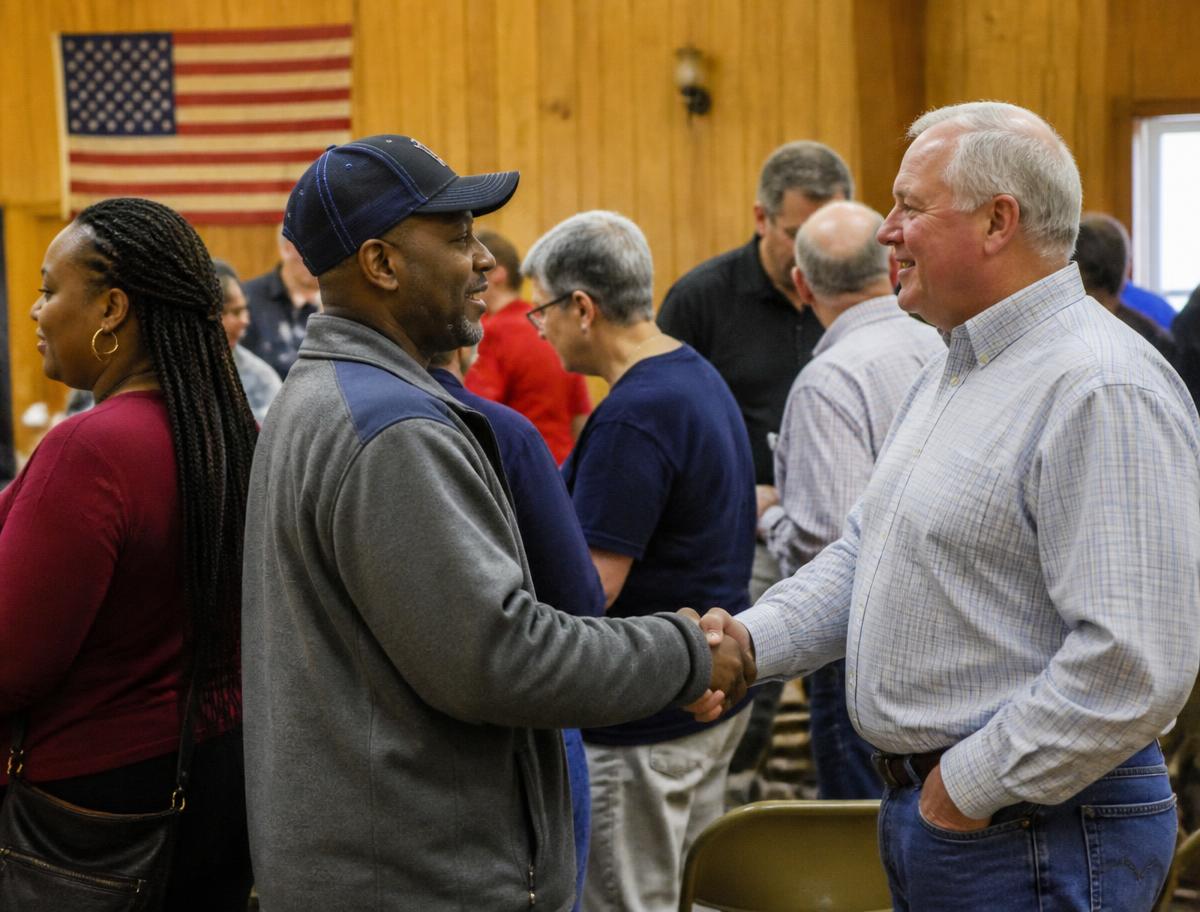Neighbors shaking hands at a local chapter meeting in a church hall